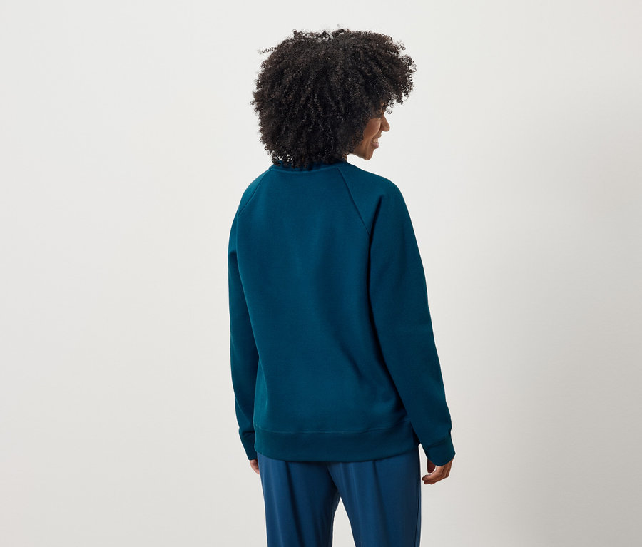 Zozadu je vidieť žena s kučeravými vlasmi v modrej mikine a nohaviciach.