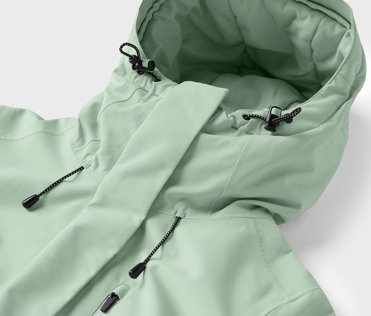 Detail svetlozelenej bundy s kapucňou a sťahovacími šnúrkami.