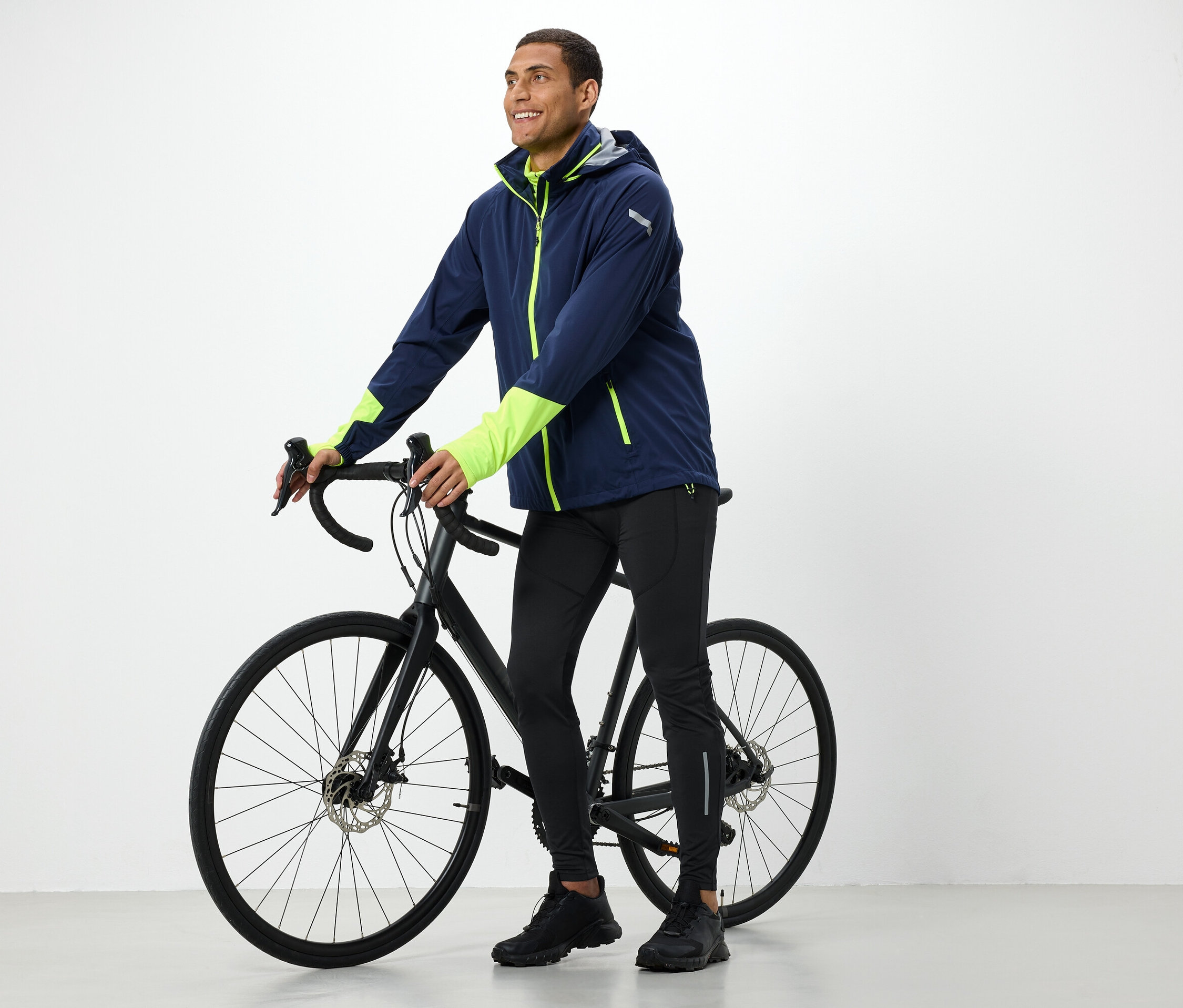 Muž v bunde drží čierny bicykel.