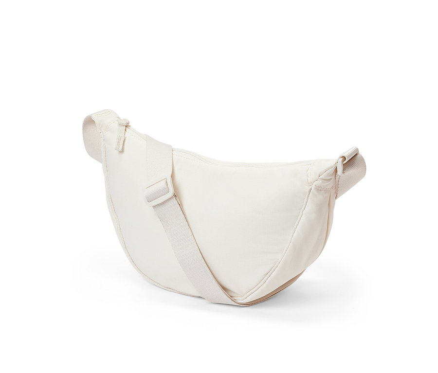 Krémová taška na plece leží na bielom pozadí.