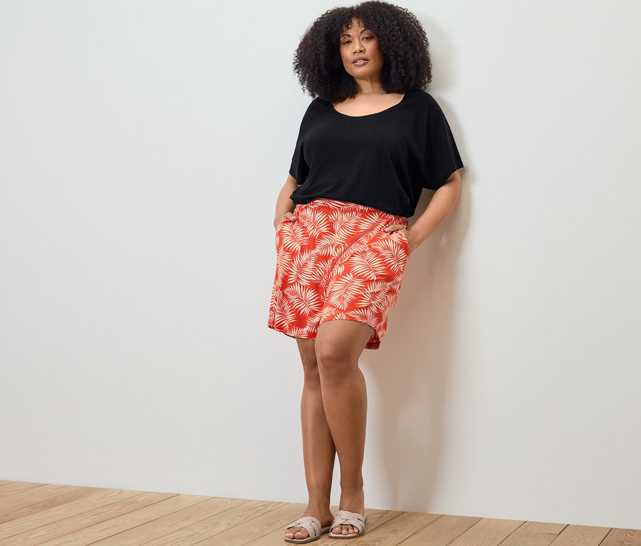 Žena pózuje v tričku z ľanovej zmesi a džersejových šortkách s potlačou.