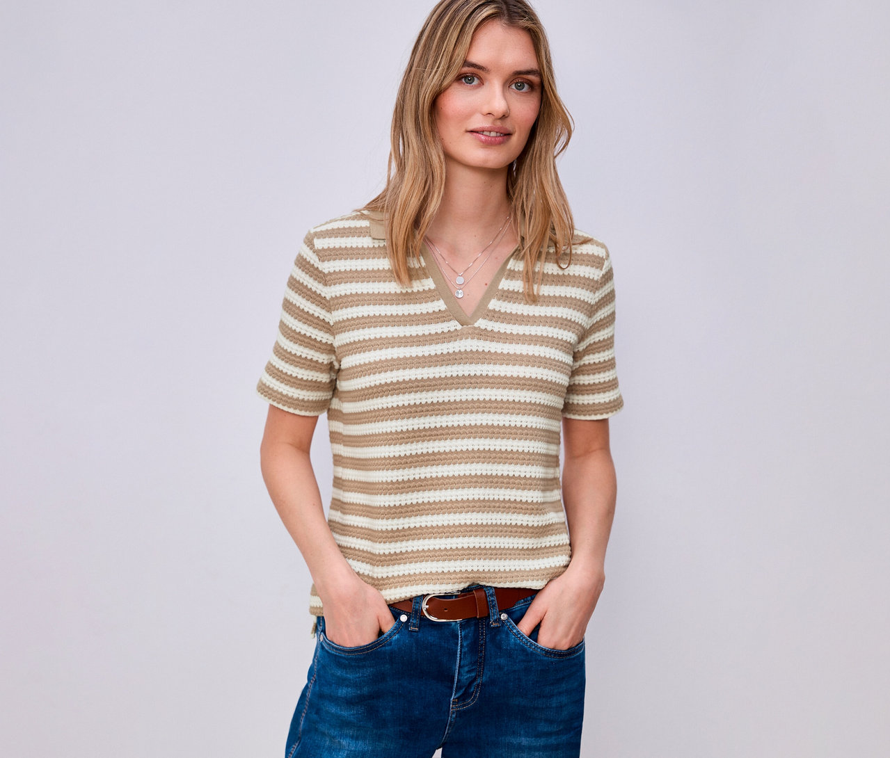 Žena v džínsoch a hnedom opasku má na sebe pruhované tričko z úpletu Street One s výstrihom do V.
