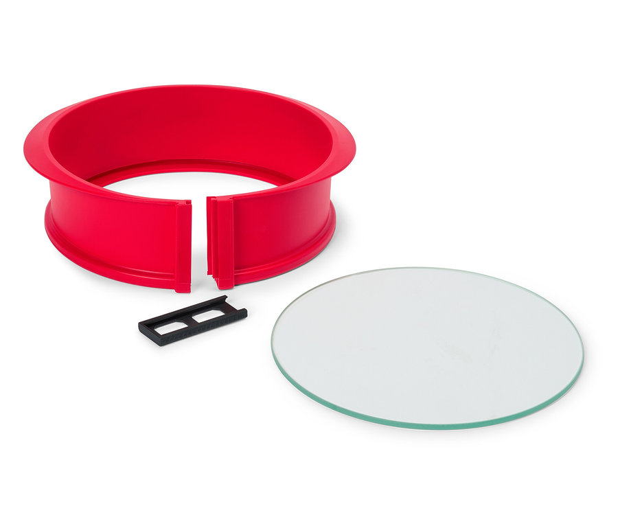 Červený okrúhly tortový rám s čiernym klipom a okrúhlou sklenenou doskou na bielom pozadí.