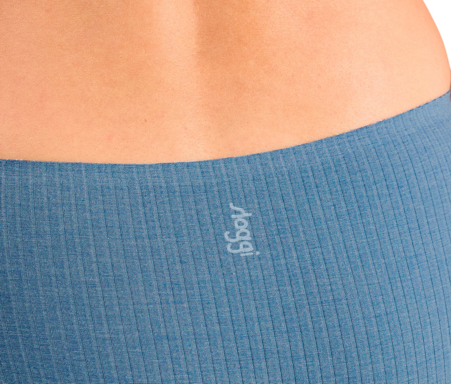 Detailný záber na spodnú časť chrbta osoby, zobrazujúci horný okraj modrých rebrovaných nohavičiek s bielym logom „sloggi“ na ľavej strane.