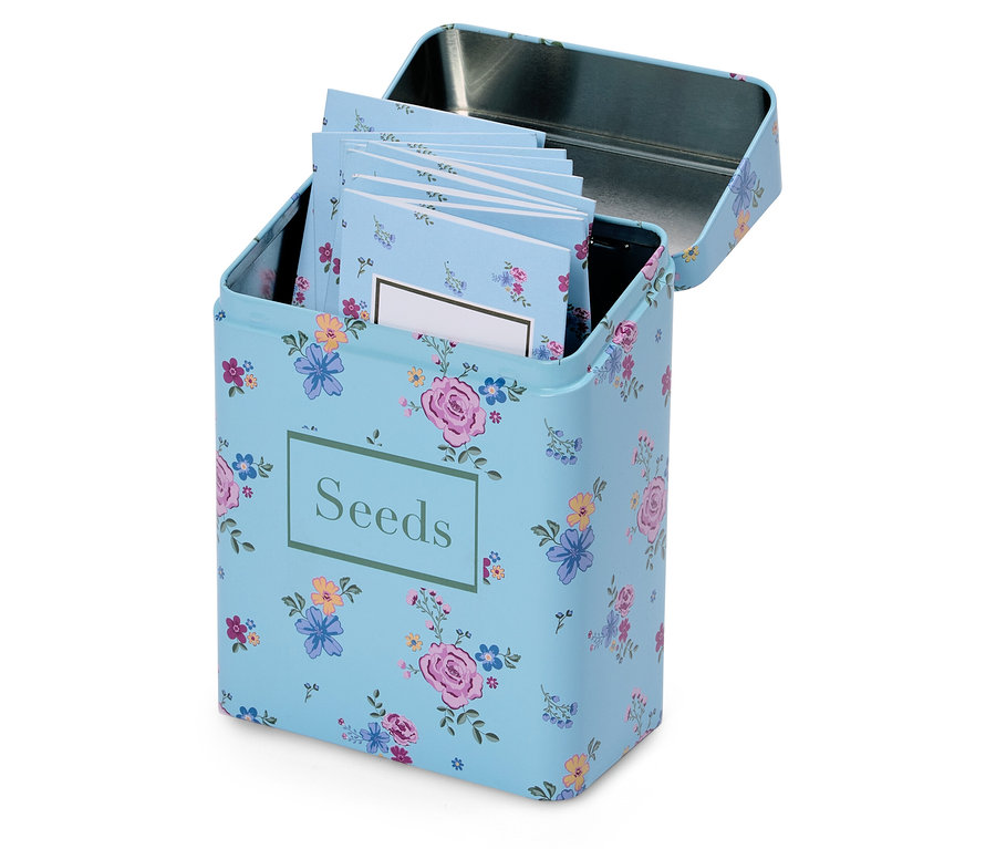 Otvorená, svetlomodrá kvetinová krabička na semená s nápisom "Seeds" a niekoľkými malými poznámkovými blokmi vo vnútri.