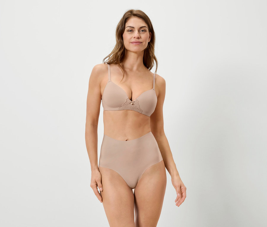 Žena má na sebe telovú podprsenku a nohavičky na bielom pozadí.