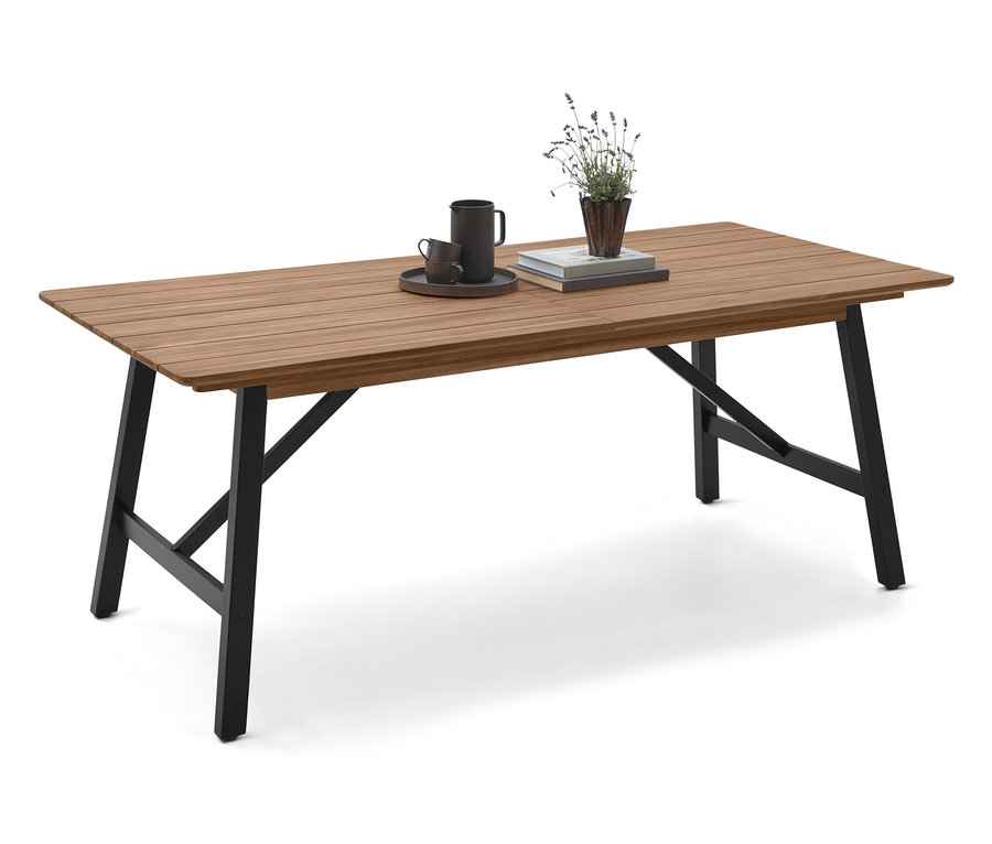 Na drevenom stole s čiernymi nohami stojí šálka, podšálka, kniha a rastlina.