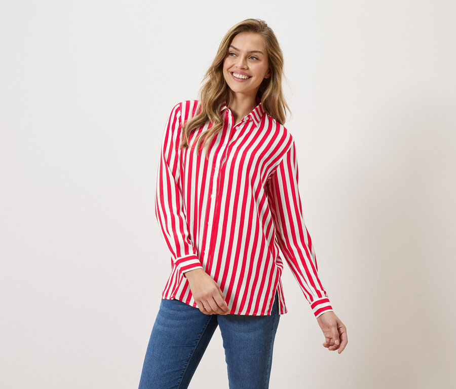 Žena má na sebe červeno-bielu pruhovanú košeľu a džínsy.