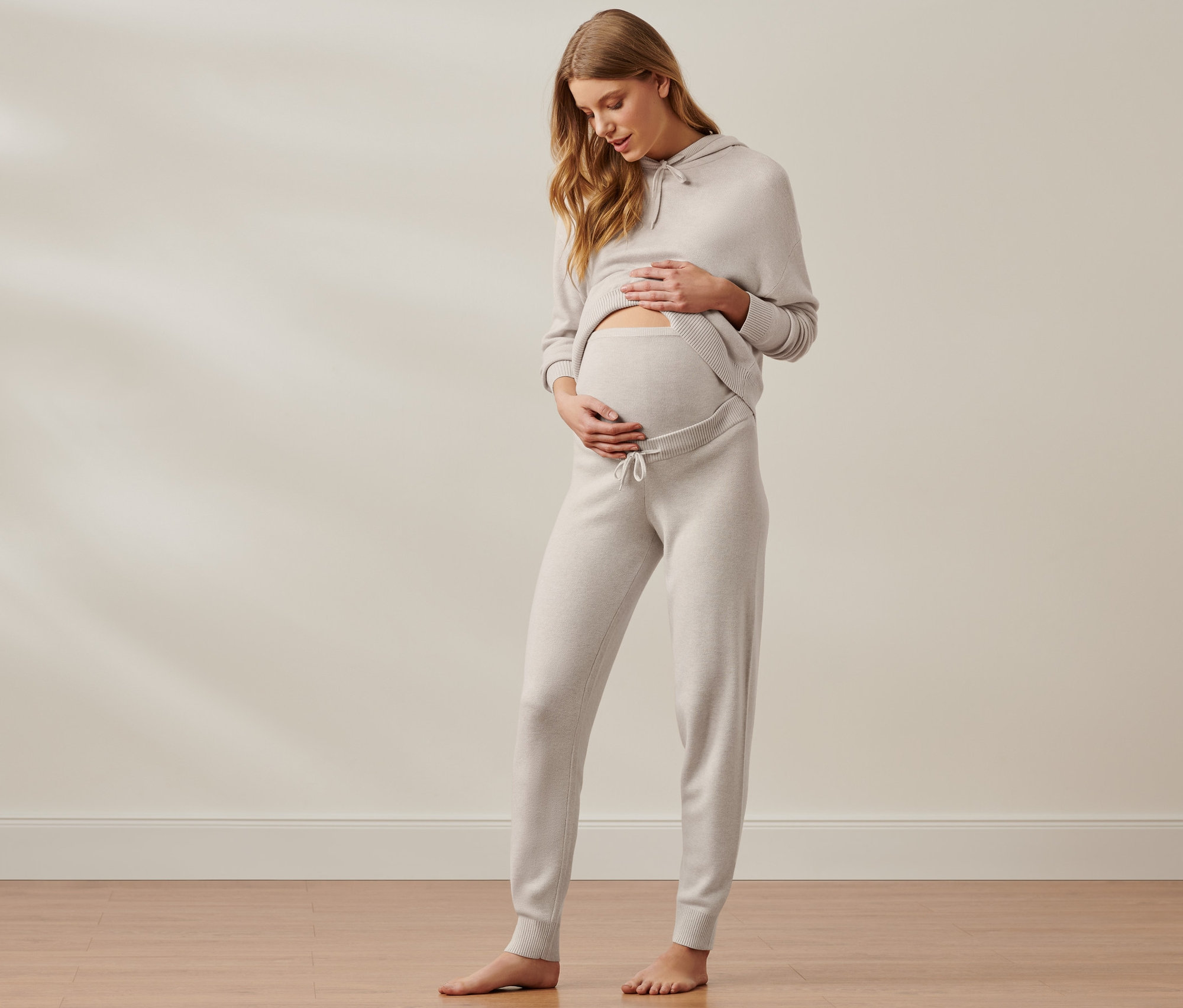 Tehotná žena hladí brucho v tehotenskej domácej súprave.