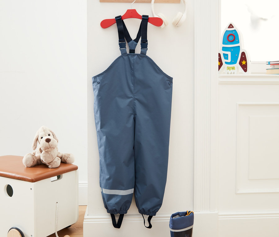 Stredne modré termonohavice do dažďa z recyklovaného materiálu visia na červenom vešiaku vedľa bielych slúchadiel.