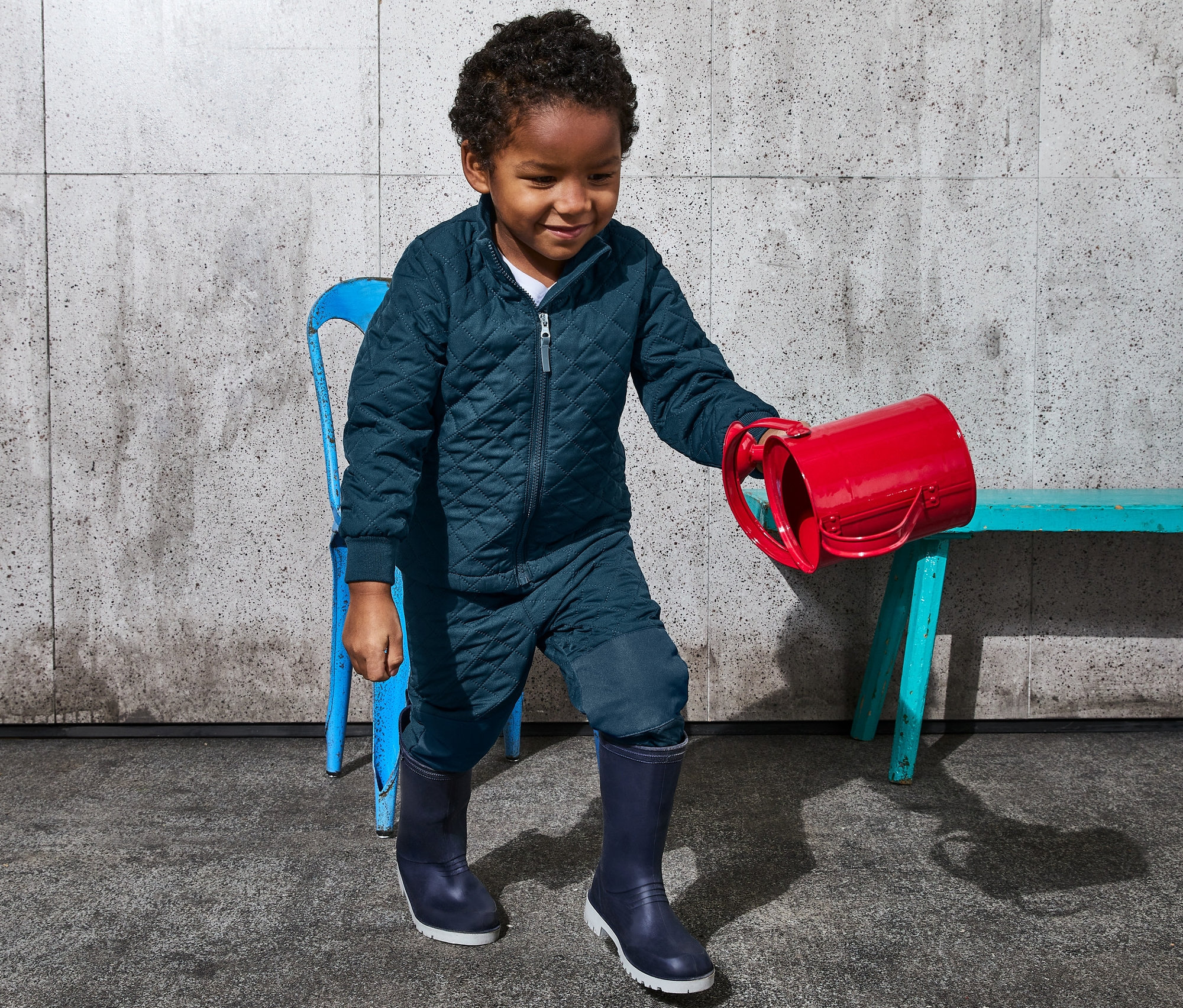 Chlapec v termosúprave z recyklovaného materiálu drží červený hrniec.