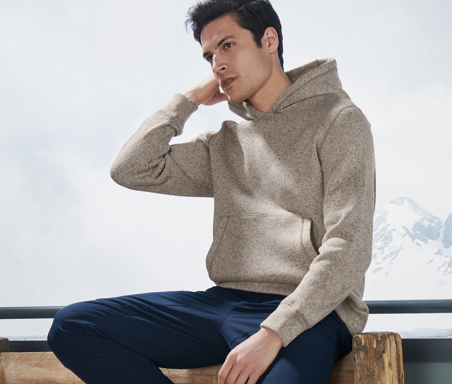 Muž sedí na lavičke a má na sebe pletenú flísovú mikinu Midlayer.
