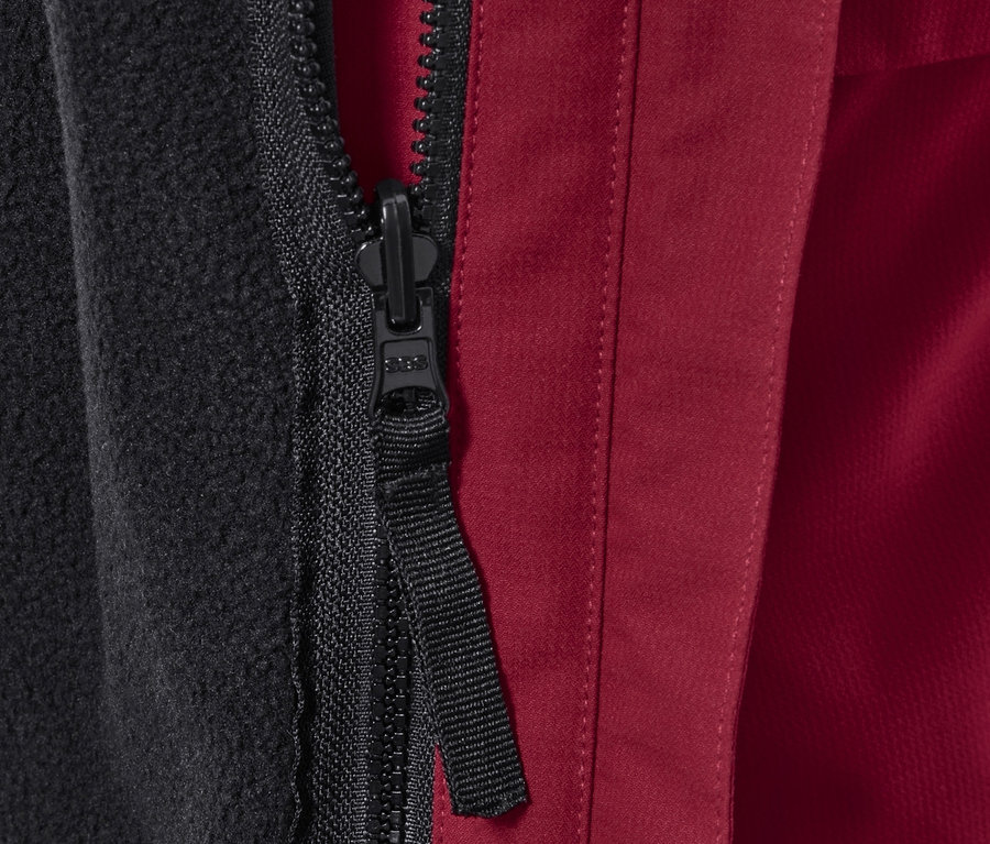 Detail zipsu bundy s čiernou flísovou podšívkou a červeným vonkajším materiálom.