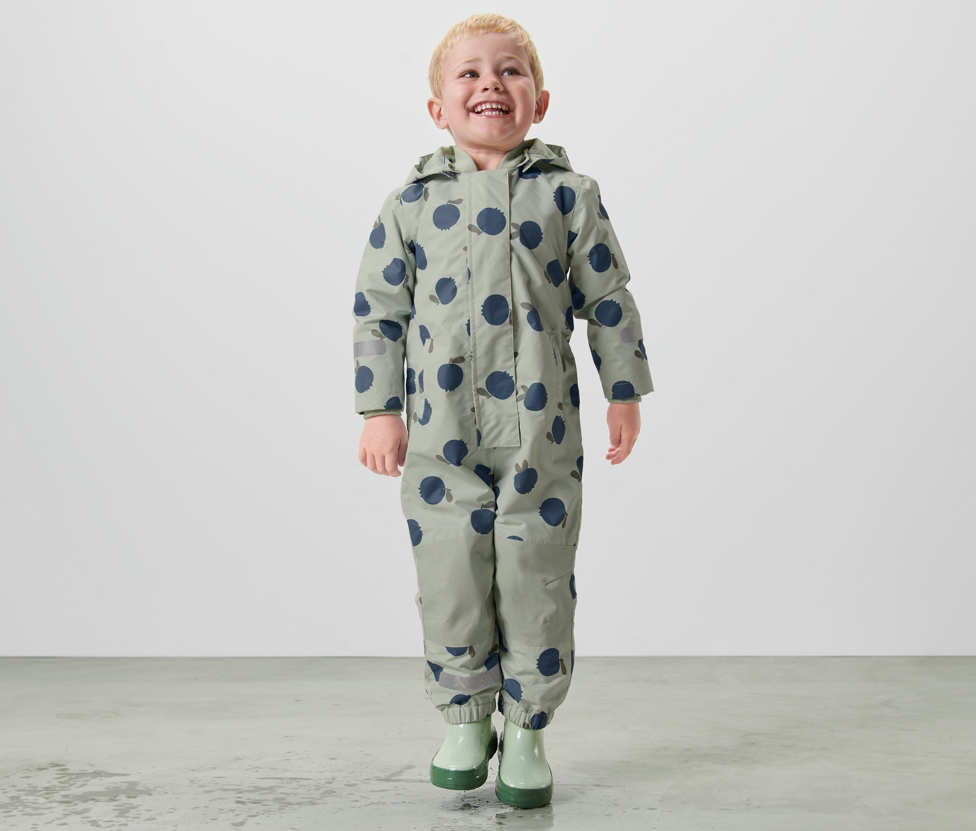 Chlapec kráča v detskom overale do dažďa.