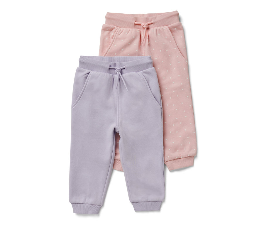Dvoje detské tepláky: jedny svetlofialové a jedny ružové s bielymi bodkami.