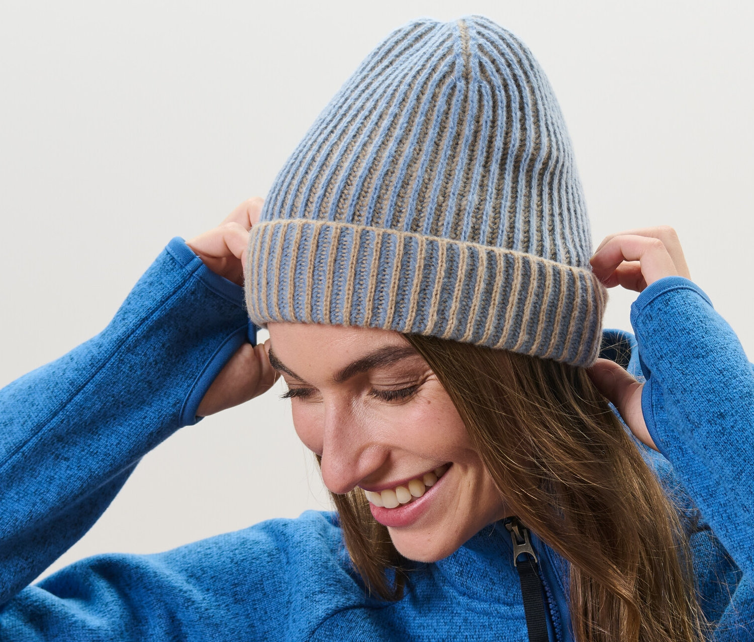 Žena si upravuje pletenú čiapku na hlave.