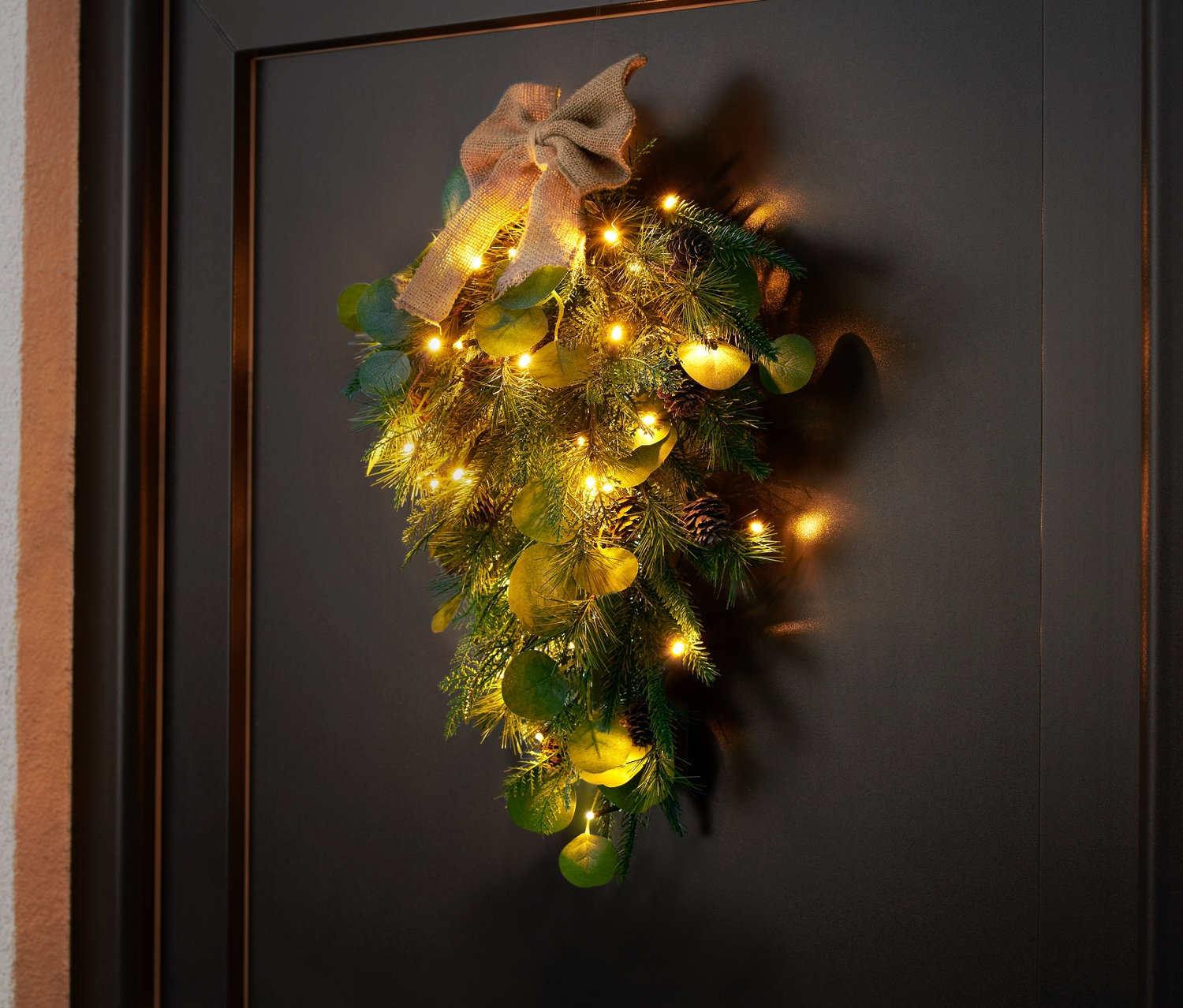 LED dekorácia na dvere visí na čiernych dverách.