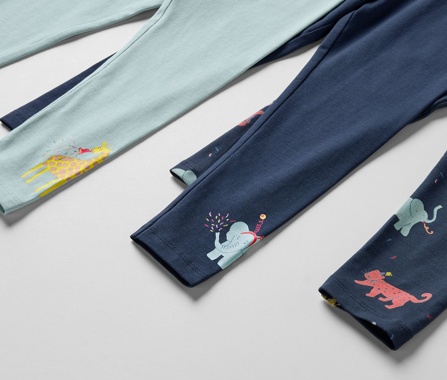 Detail troch detských legín, jedny svetlomodré so žirafou, jedny tmavomodré so slonom a jedny tmavomodré so zvieratami.