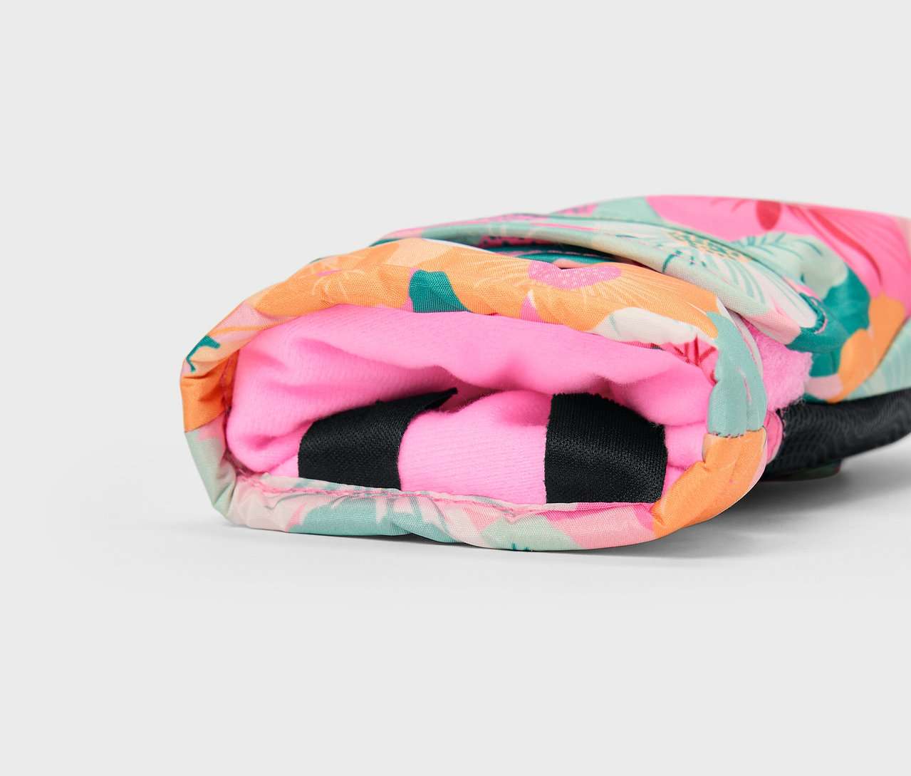 Detail farebného obalu s tropickým vzorom a ružovým vnútrom.