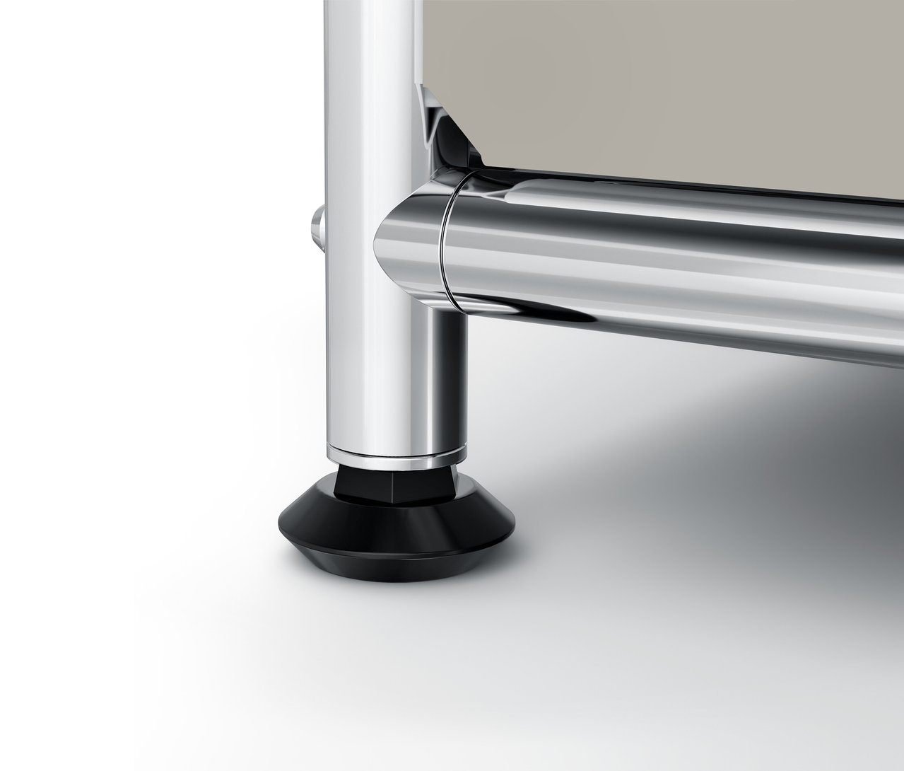 Detail chromovanej nohy a čierneho podstavca nábytku.