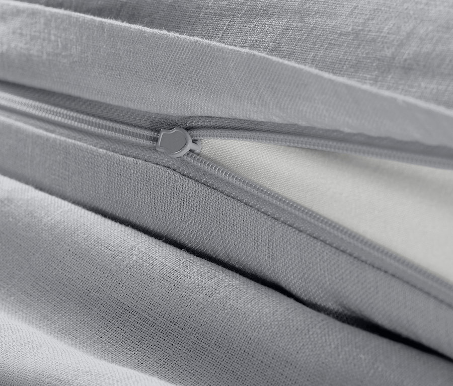 Detail šedej ľanovej posteľnej bielizne nadmernej veľkosti so zipsom.