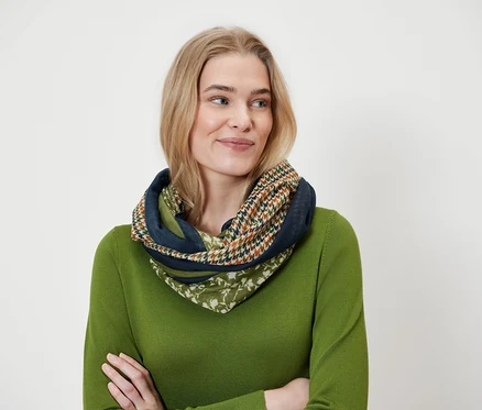 Blondína má na sebe viacfarebný šál a zelený sveter.