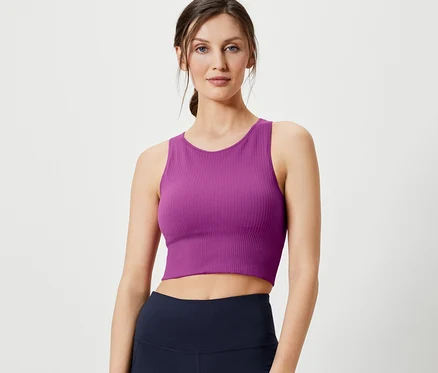 Žena pózuje v bezšvovej podprsenke bralette a tmavomodrých legínach.