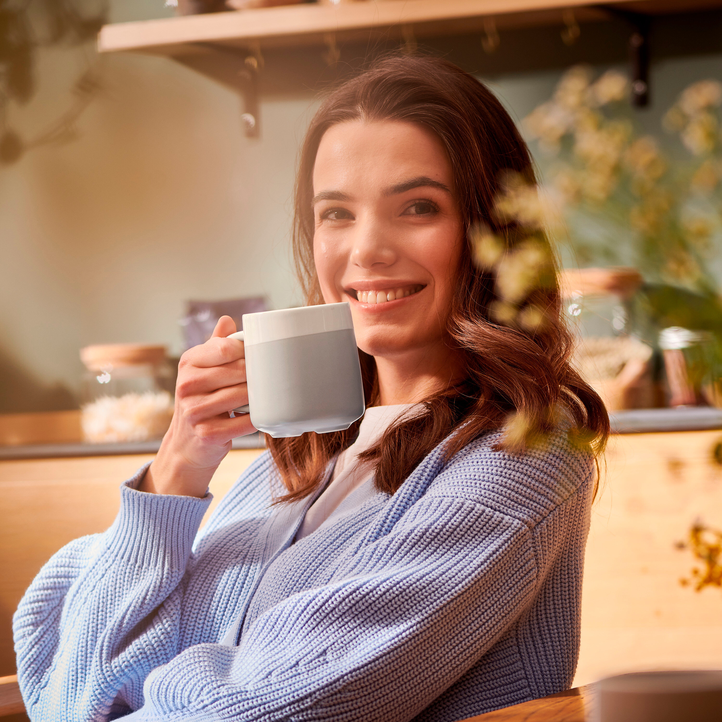 Usmievajúca sa žena drží sivo-biely hrnček.