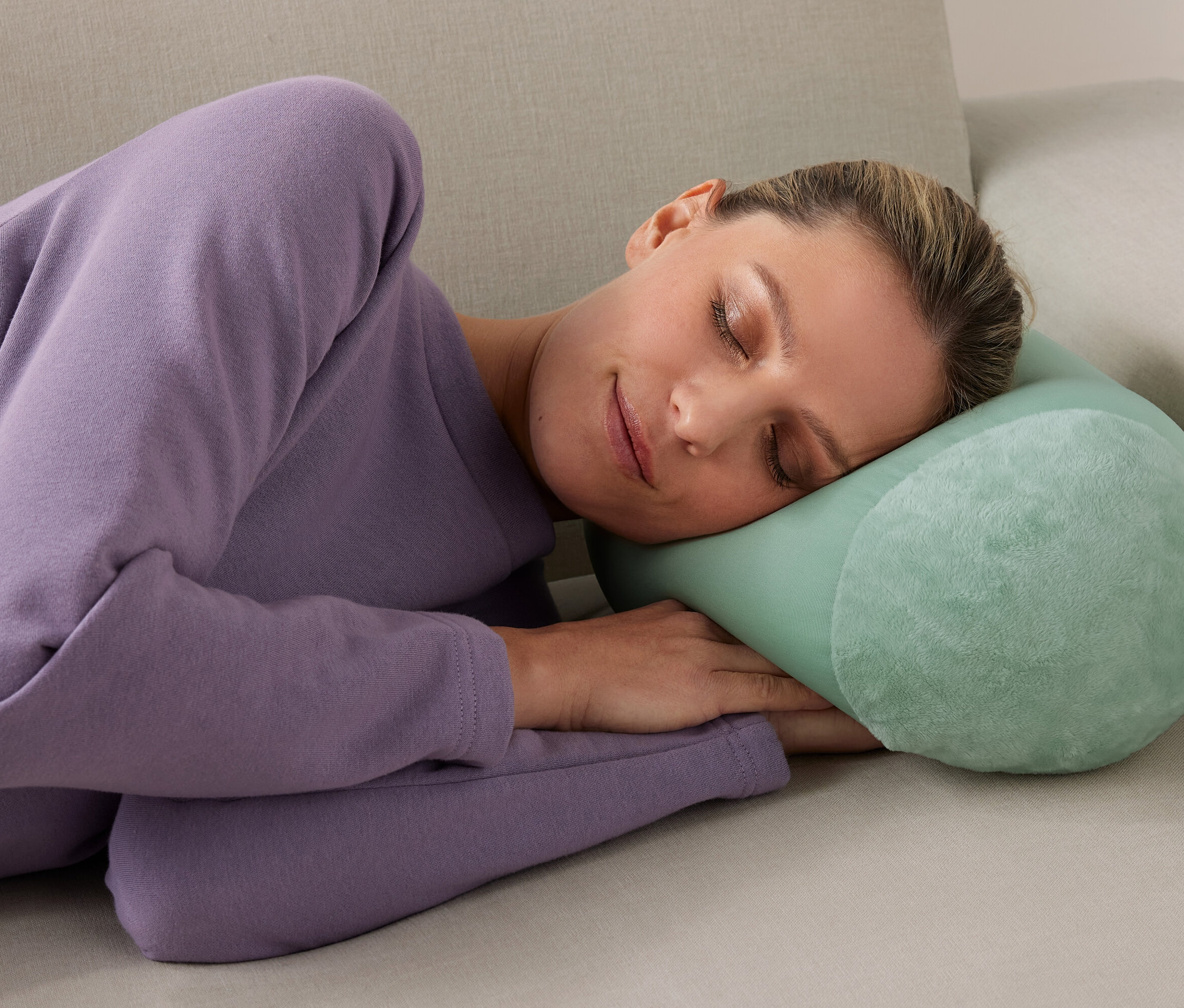 Žena spí na gauči s relaxačným vankúšom.