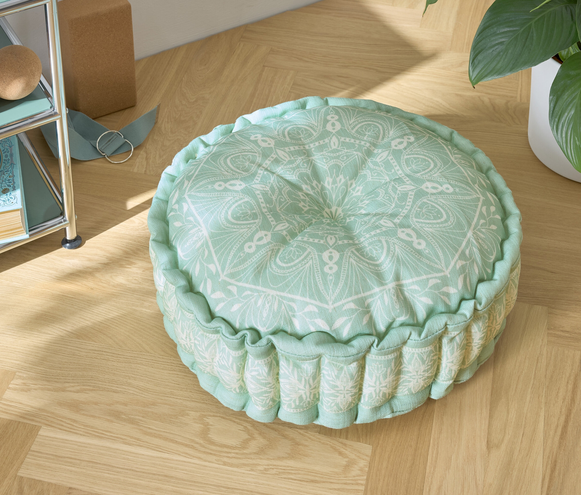 Zelený podsedák s bielym vzorom na drevenej podlahe.