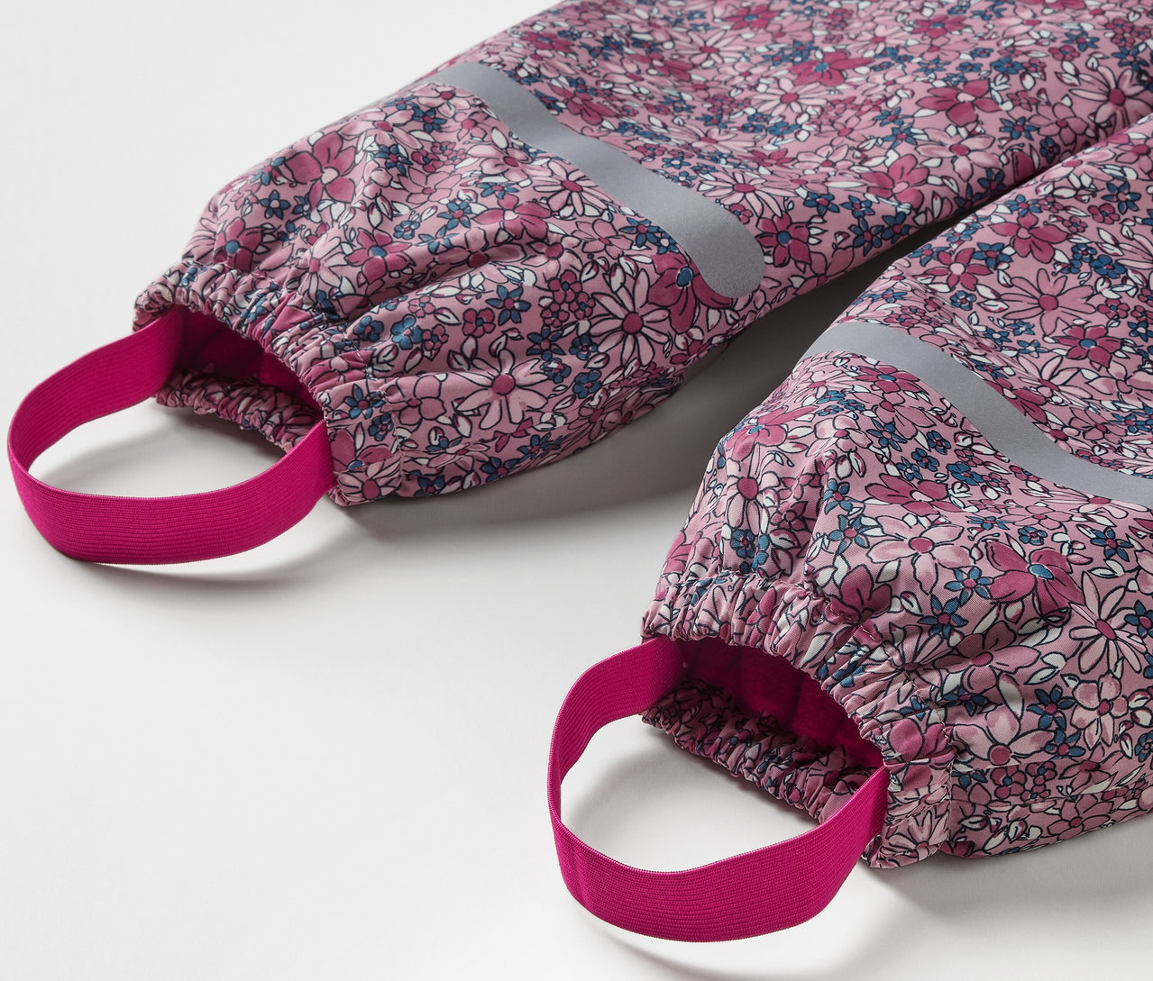 Detail detských termo nohavíc do dažďa s kvetinovým vzorom a reflexnými prvkami.