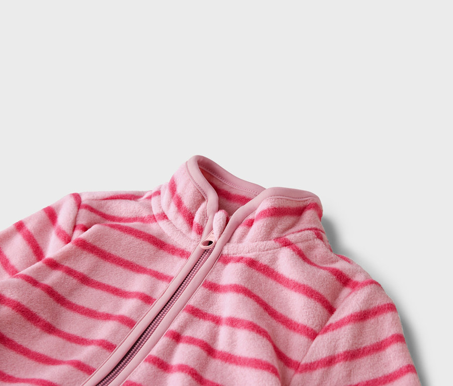 Detail ružovej fleecovej bundy s horizontálnymi tmavoružovými pruhmi a zipsom.
