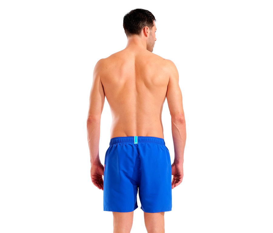 Pohľad zozadu na muža v modrých plavkách na bielom pozadí.