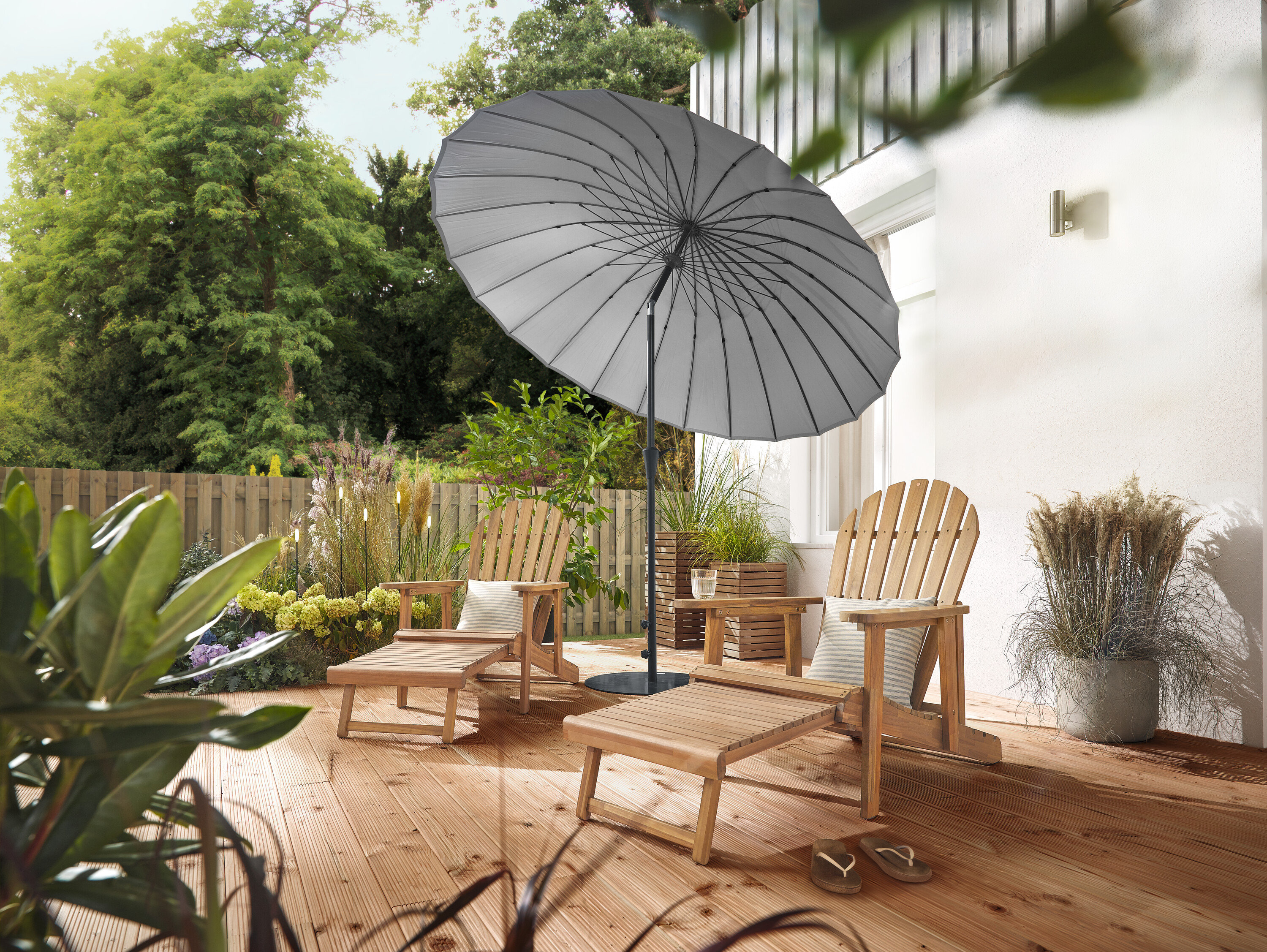 Na terase stoja dve prírodné Adirondack relaxačné kreslá s vyťahovacou opierkou nôh, lemované 2 Pflanzsäulen »Tinus« a 5 LED solárnymi bodcami. Svetlosivý slnečník Leco Shanghai poskytuje tieň.