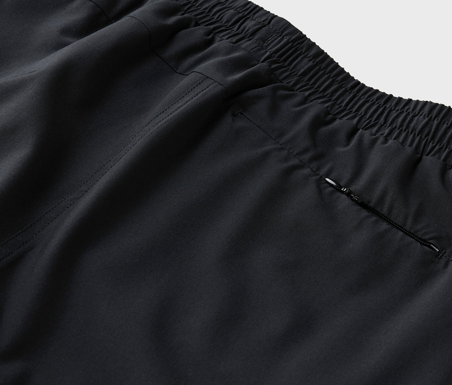 Detailný záber zadnej časti čiernych nohavíc s elastickým pásom a vreckom na zips.