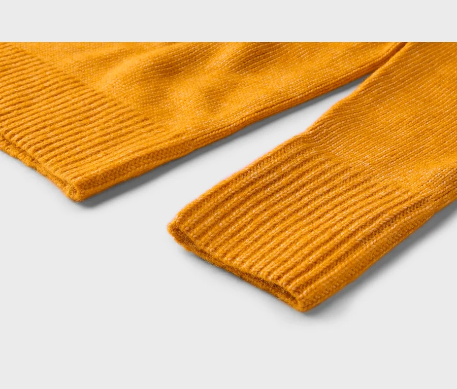 Detail jasne žltého pleteného materiálu, zobrazujúci rebrovaný okraj a rebrovanú manžetu rukáva.