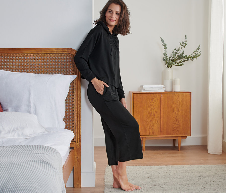 Žena opretá o posteľ v čiernej sedemosminovej domácej súprave.