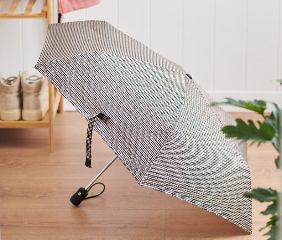 Na podlahe leží zložený automatický dáždnik.