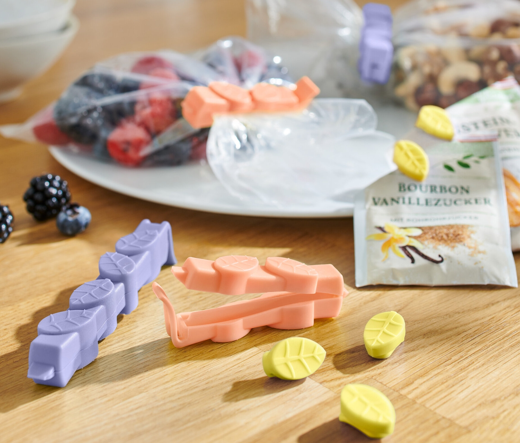 Na drevenom stole leží 15 zapínacích spôn rôznych farieb, vrecká s ovocím, orechmi a vanilkovým cukrom.