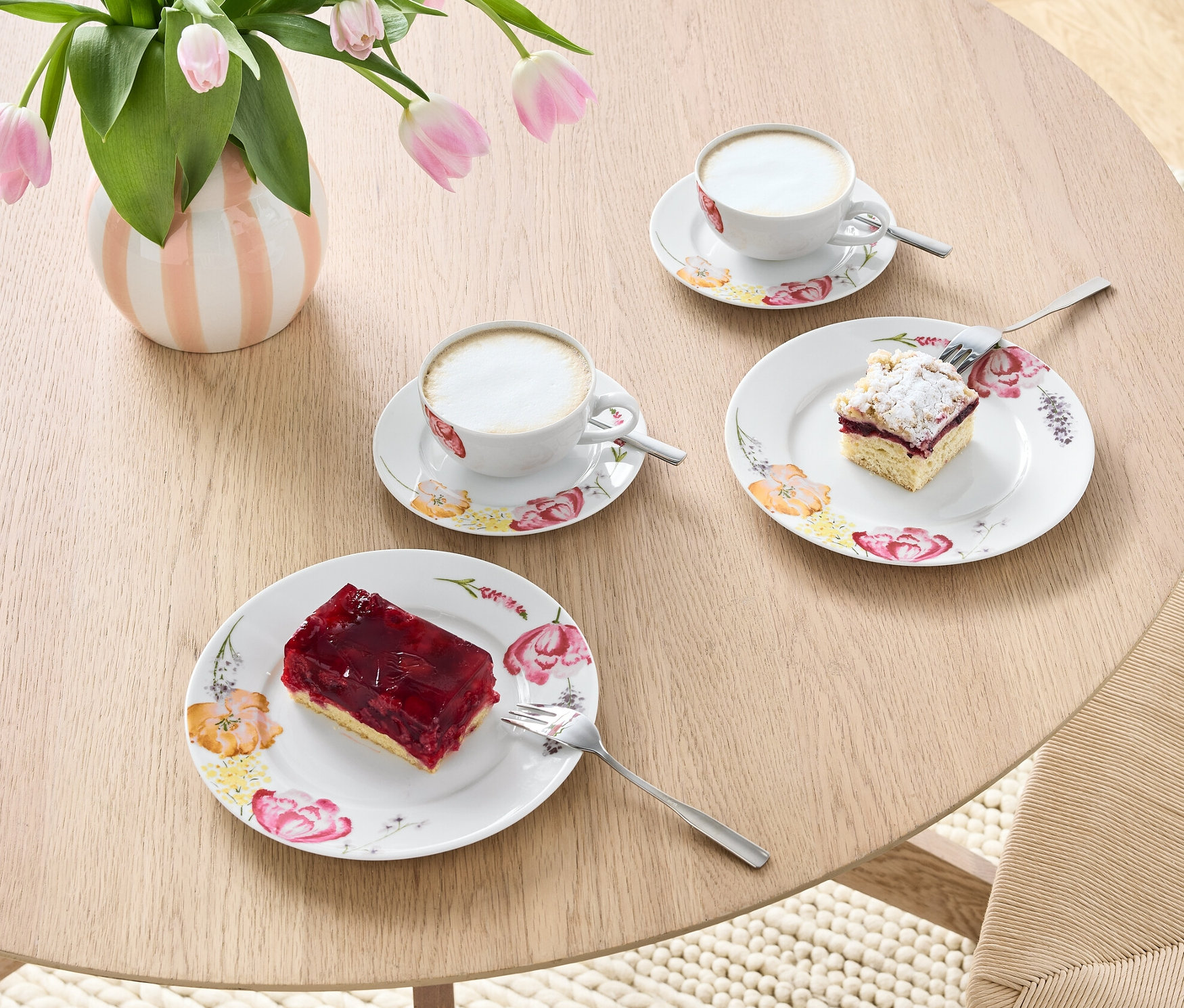 Na stole stojí váza s tulipánmi a 6-dielny kávový servis s kávou a zákuskami.