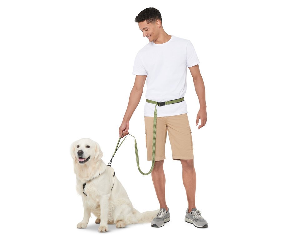 Muž drží vôdzku pre psy s nastaviteľnou dĺžkou, zatiaľ čo sedí zlatý retriever.