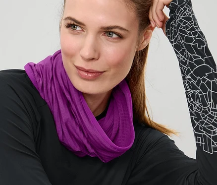 Žena sedí a nosí fialovú multifunkčnú šatku.