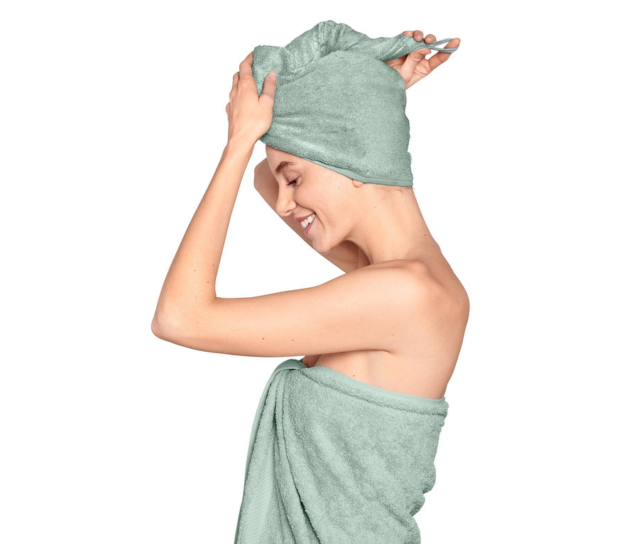 Žena si dáva na hlavu svetlomodrý uterákový turban.