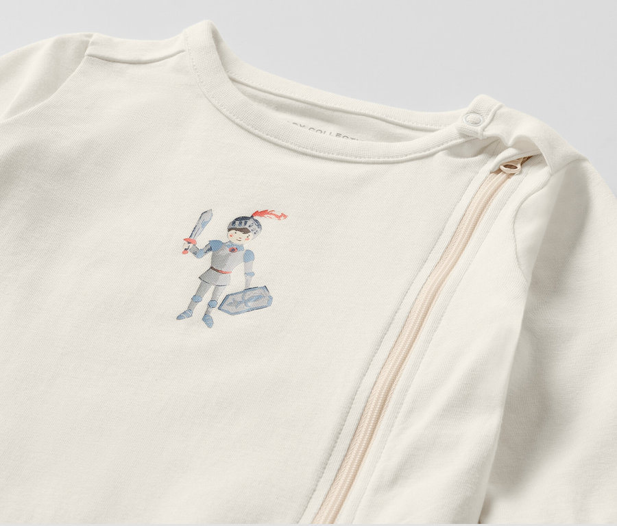 Detail bieleho pyžamá pre bábätká s obrázkom rytiera.