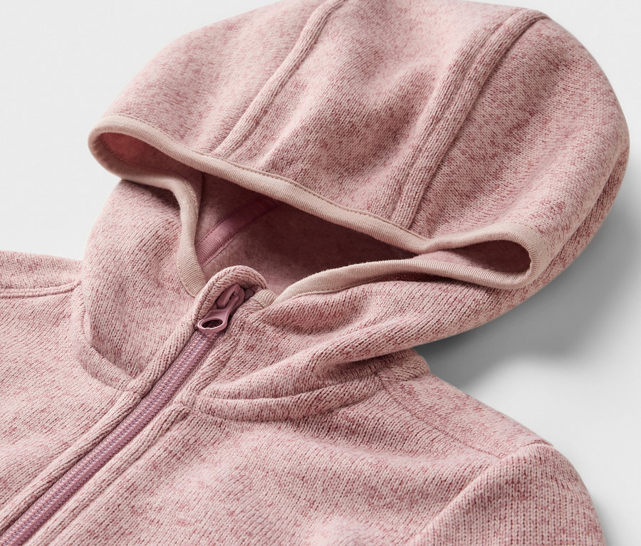 Detail detskej mikiny z pleteného fleecu s kapucňou a zipsom.