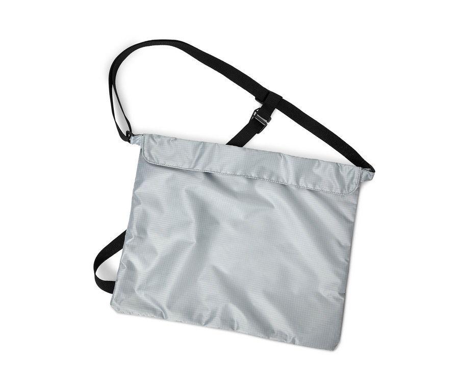 Zvislý záber striebornej nákupnej tašky na bicykel s čiernymi popruhmi na bielom pozadí.