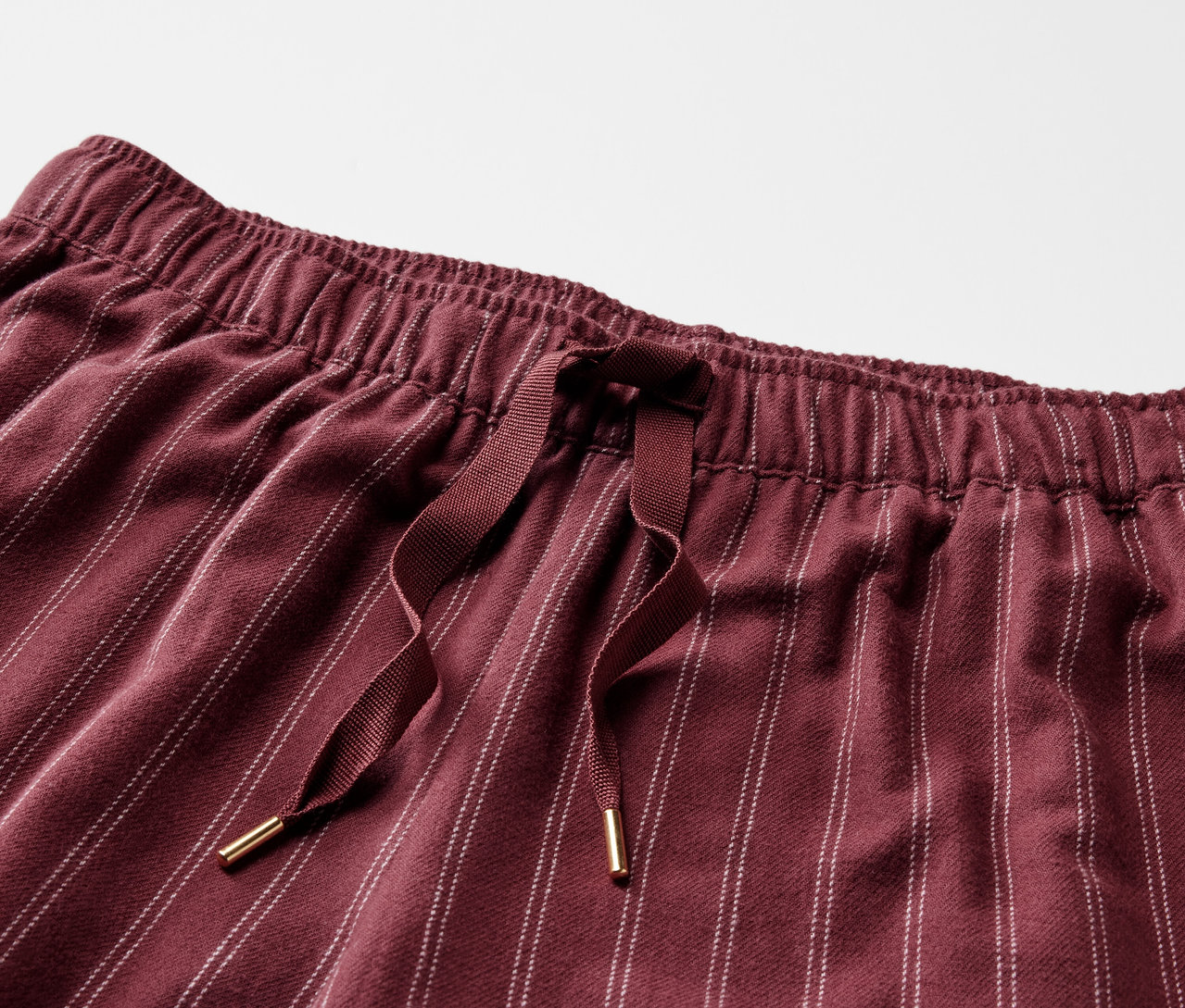 Detail bordových pruhovaných nohavíc s elastickým pásom a sťahovacou šnúrkou.