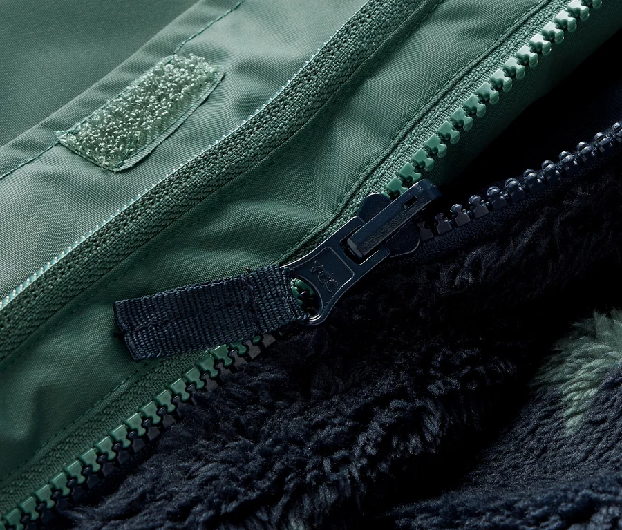 Detailný záber na zips a suchý zips zelenej detskej zimnej bundy 3 v 1.
