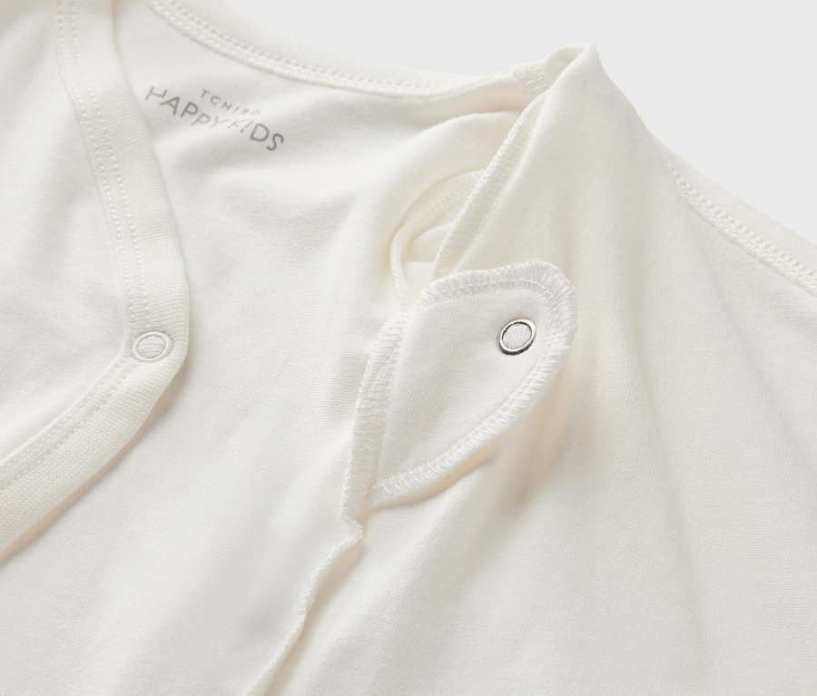 Detail bieleho body pre bábätká s možnosťou prispôsobenia veľkosti s cvokom.