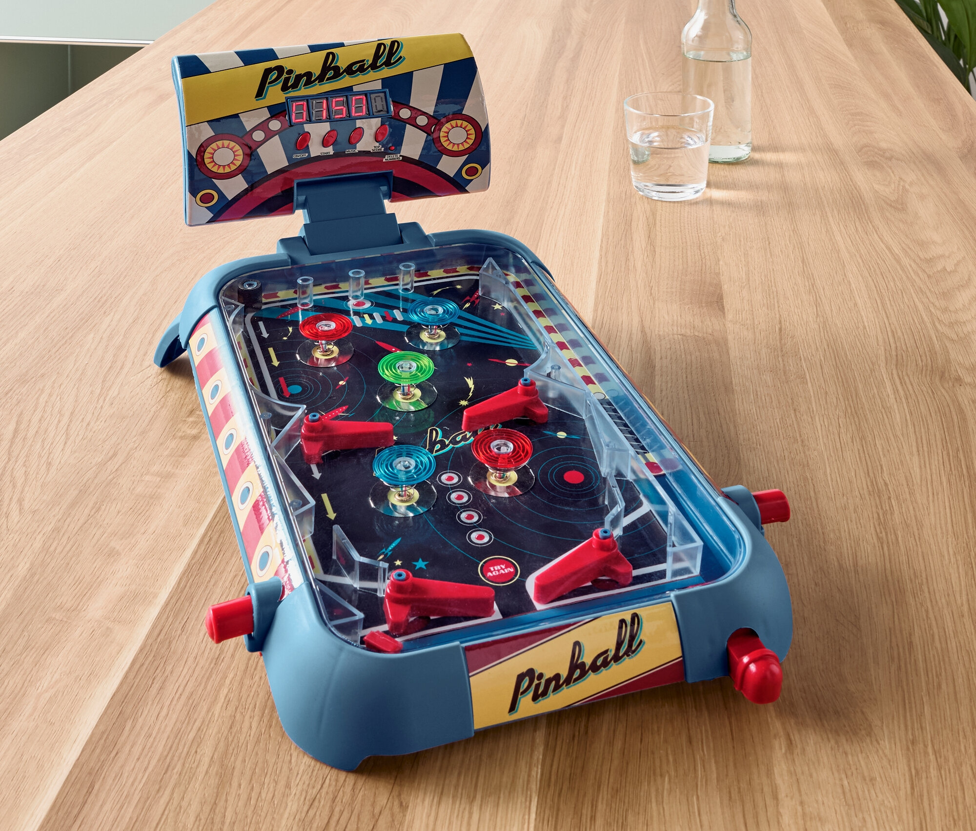 Modrý mini pinballový automat na drevenom stole.
